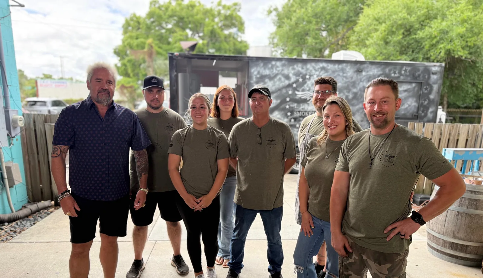 Guy Fieri with Chef Bryan Jacobs and the Liberty Smokehouse crew in front of the smoker trailer