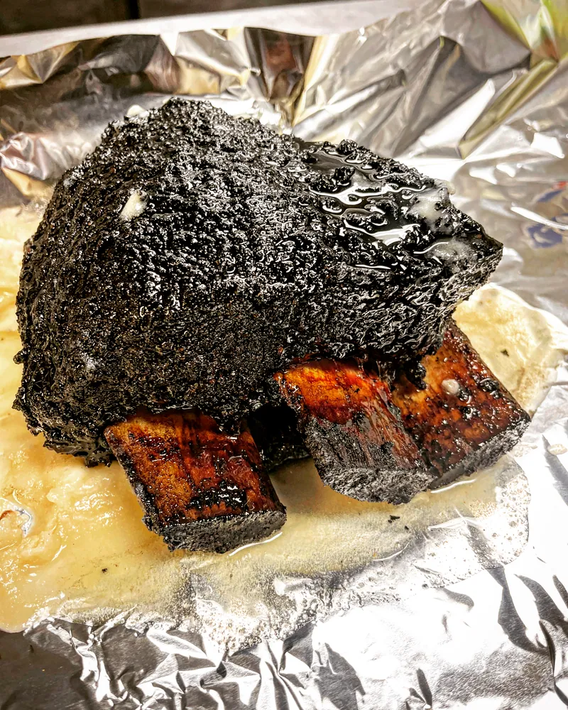 A smoked beef rib with deep black bark
