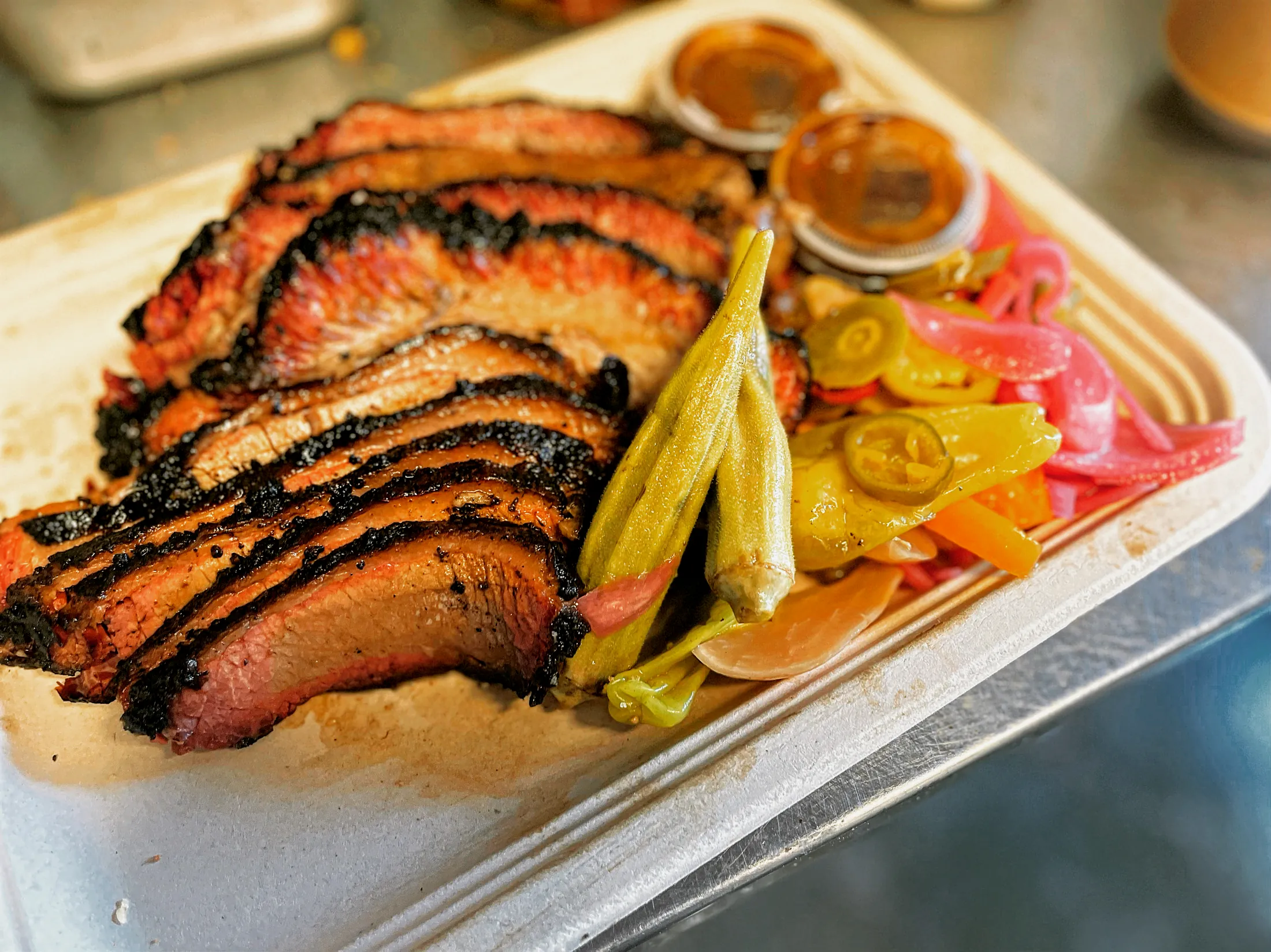 Sliced smoked brisket with pickled peppers and house sauces