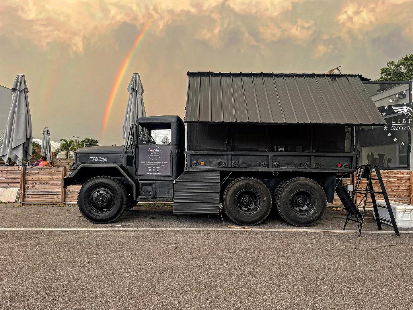 The truck parked outside a beer garden under a double rainbow